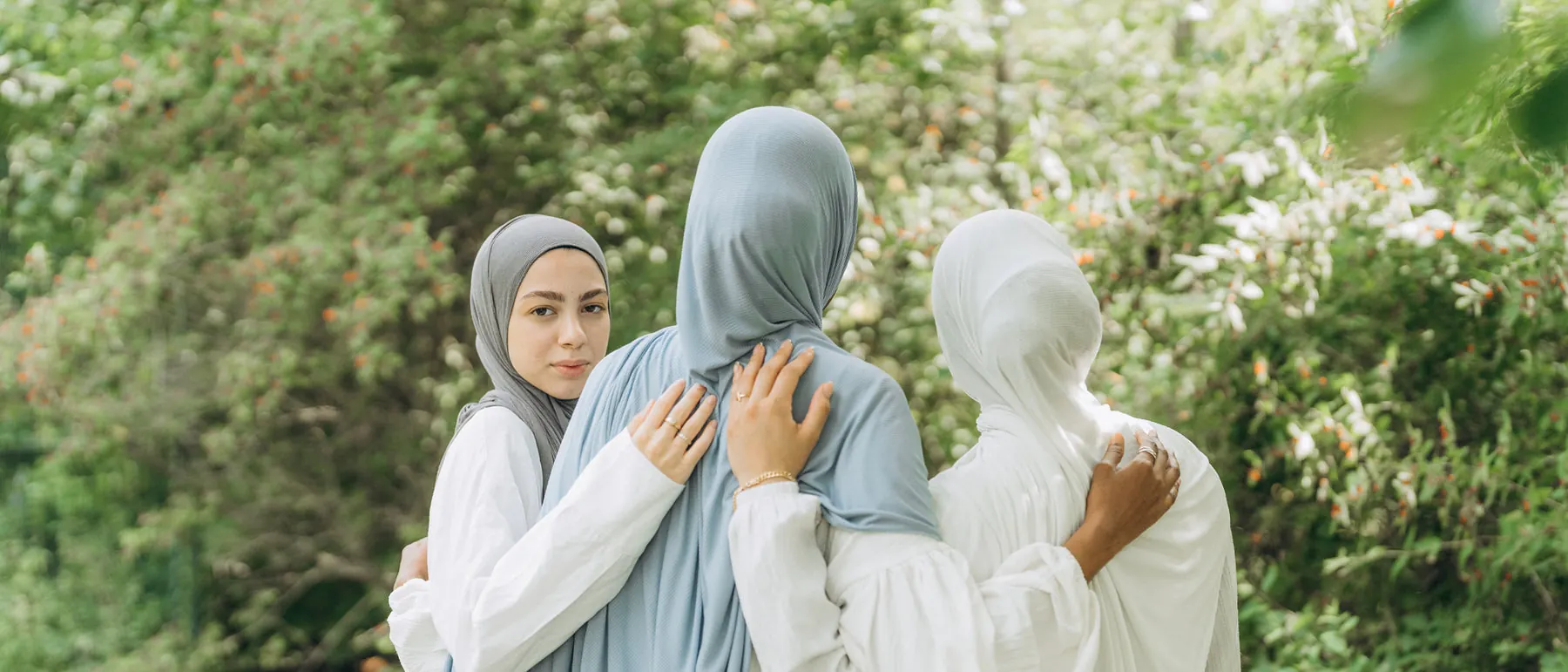 Three women in VoileChic hijabs holding each other in a garden